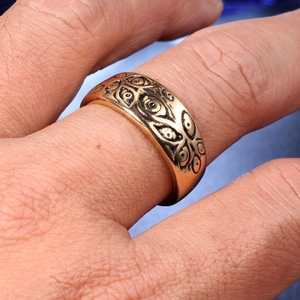 Macro view of vintage gold eye-patterned titanium steel ring with relief texture