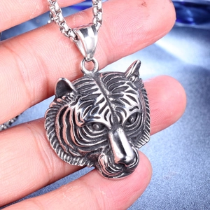 Macro detail of a vintage tiger head pendant in stainless steel with an oxidized finish
