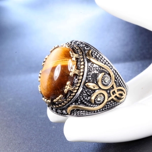 Vue macro d'une bague punk vintage pour homme avec œil de tigre ovale et détails floraux