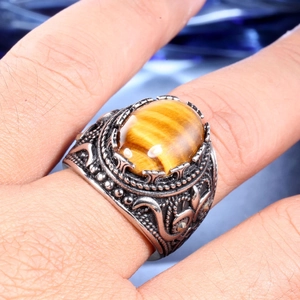 Détail macro d'une bague vintage en acier pour homme avec pierre oeil de tigre et reliefs