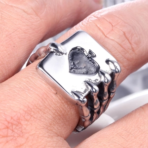 Macro detail of gothic men's ring with silver skull bone claws holding an Ace of Spades