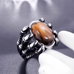 Macro shot of tiger eye stone held by a retro silver dragon claw on a men's ring