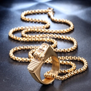 Macro shot of gold lighter-shaped ring and matching round box chain on gray texture