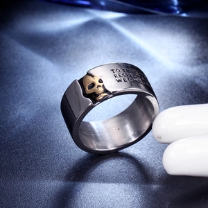 Macro shot of silver stainless steel ring with golden skull relief and engraved text