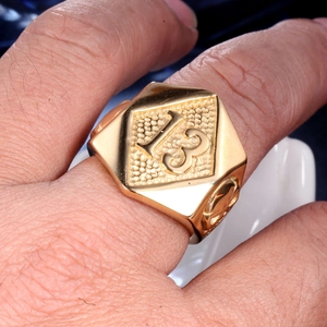 Macro shot of men's golden hexagon ring with number 13 relief and vintage carvings