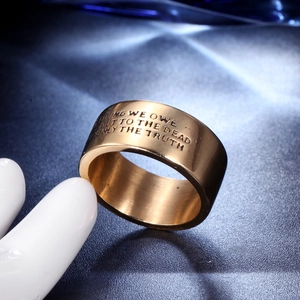 Detail of wide gold stainless steel band with engraved Voltaire quote on dark background