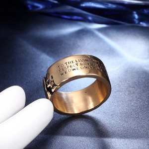 Macro shot of wide gold stainless steel ring with engraved black letter quote