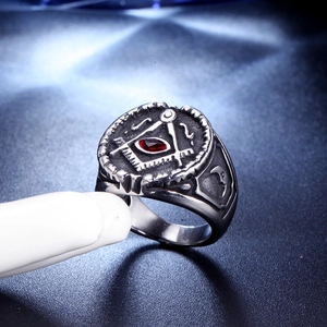 Macro de bague maçonnique argentée avec pierre rouge centrale et symboles compas