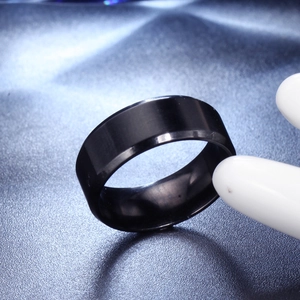 Gros plan d'une bague en titane noir mat avec bords polis sur fond bleu