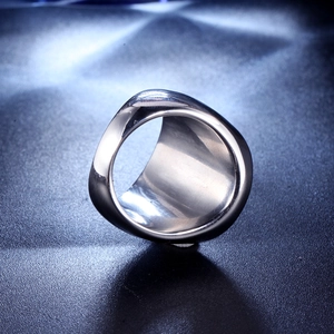 Detailed close-up of wide polished stainless steel band ring on blue textured background