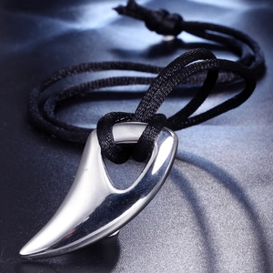 Polished stainless steel horn pendant with black braided rope necklace on dark surface