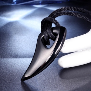 Macro shot of polished black horn pendant with smooth surface and woven black necklace cord
