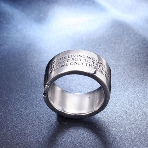 Primer plano macro de anillo de acero inoxidable con grabado filosófico sobre fondo oscuro