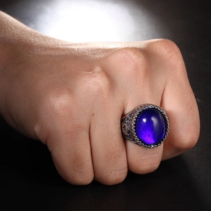 Dettaglio macro di un anello retrò da uomo con pietra ovale viola e lati incisi