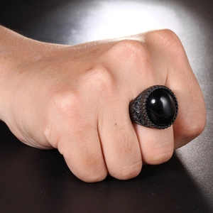 Dettaglio anello in rilievo retrò con grande pietra nera sulla mano di un uomo in nero