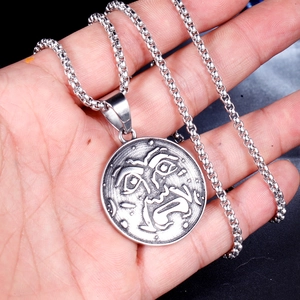 Detail view of vintage sun and moon face engraving on a rustic steel coin pendant necklace