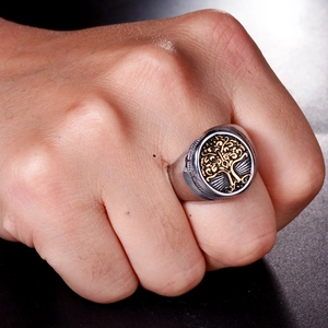 Macro detail of men's stainless steel signet ring with golden tree of life engraving