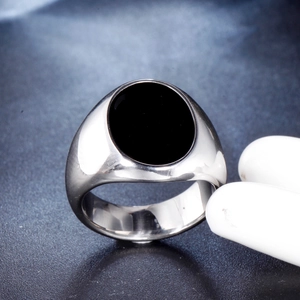 Detailed close-up of a men's stainless steel signet ring with an oval black onyx stone