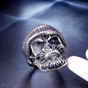 Macro shot of stainless steel skull ring with beanie and beard in vintage gothic style