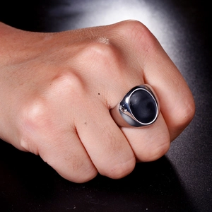 Detail of silver stainless steel signet ring for men with black oval stone and side diamond