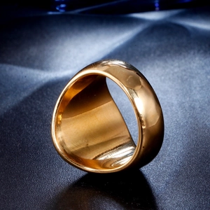 Macro close-up of polished gold-plated stainless steel wide ring on dark background
