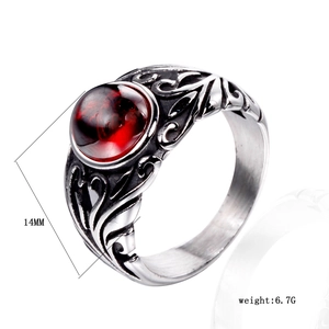 Detail view of vintage stainless steel ring with red gemstone and floral engraving