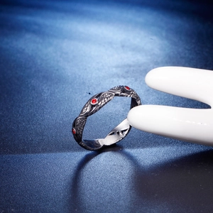 Vintage feather titanium steel ring with three red zircon stones on a blue background