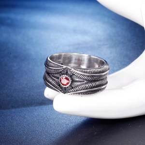 Bague vintage en acier inoxydable avec plume et pierre rouge sur modèle de main
