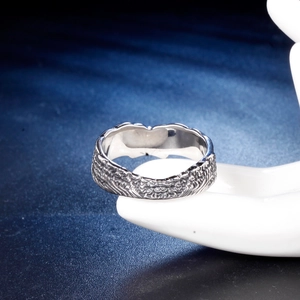 Vintage titanium steel cross ring with intricate relief textures on blue background