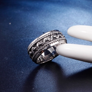 Vue macro d'une bague en acier titane argenté avec chaîne tressée et bords cordés
