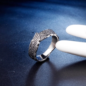 Close-up of vintage titanium steel ring with intricate cross and feather carvings