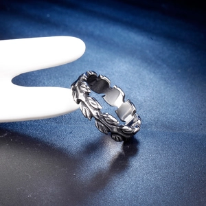 Vintage stainless steel feather ring for men featuring intricate leaf textures on a stand