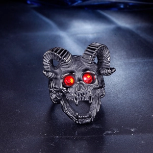 Macro shot of punk ram skull ring with red gemstone eyes and black matte finish