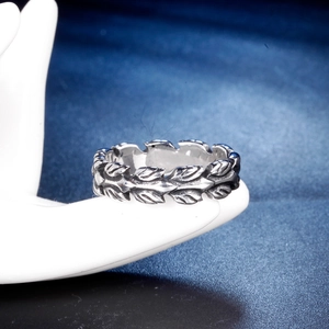 Detailed view of vintage stainless steel feather ring with aged finish on a hand model