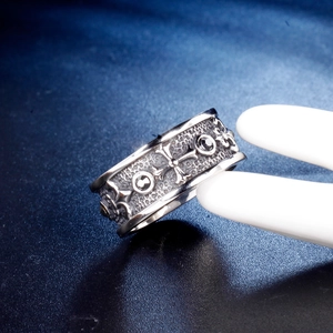 Macro detail of gothic stainless steel wide ring with cross and fleur-de-lis engraving