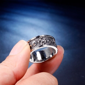 Macro detail of vintage fleur-de-lis relief on a stainless steel ring with antique finish