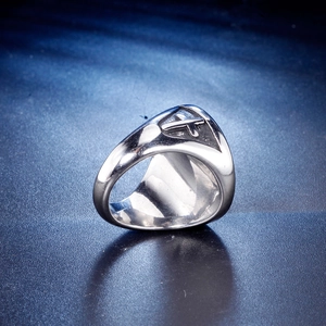 Macro detail of silver stainless steel ring featuring an engraved cross symbol on side