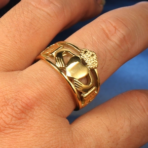Dettaglio macro dell'anello Claddagh dorato con corona e cuore indossato