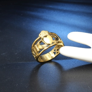 Dettaglio anello Claddagh dorato con motivo cuore-corona e design traforato raffinato