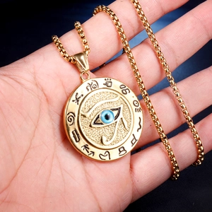 Détail du pendentif Œil d'Horus avec œil bleu et symboles égyptiens tenu à la main