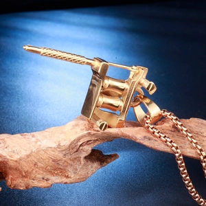 Gros plan du pendentif machine à tatouer doré sur un support en bois naturel