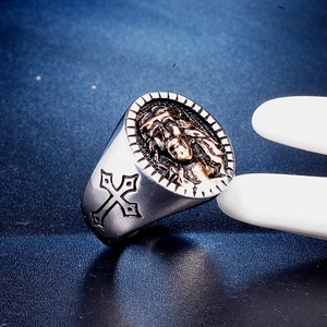 Macro shot of silver and gold stainless steel ring with Jesus relief and cross detail