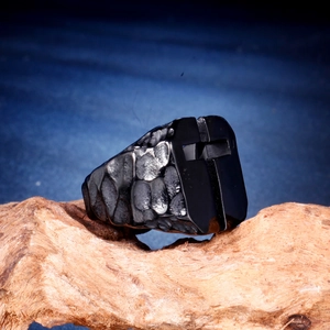 Détail d'une bague noire pour homme avec texture martelée et motif croix ajourée
