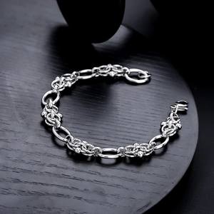 Polished titanium steel link bracelet with hollow textured rings on a black wood stand