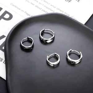 Pendientes de aro geométricos plateados para hombre y mujer en un plato negro mate