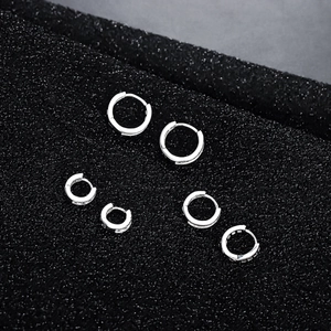 Tres pares de pendientes de aro plateados brillantes con piedras sobre un fondo oscuro