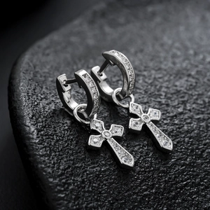 Boucles d'oreilles créoles croix en argent avec zircons blancs sur fond de roche texturée