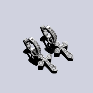 Boucles d'oreilles croix en argent avec zircons sur une surface réfléchissante noire