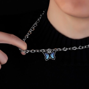Blue butterfly pendant necklace in titanium steel on a black turtleneck sweater