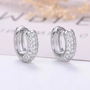 Detailed close-up of silver-tone huggie earrings featuring full pave cubic zirconia stones